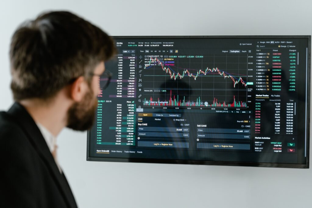 Service-1-min (1) A businessman in a suit looks at a screen displaying stock market charts and data analysis.